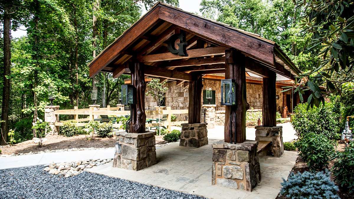 Four logs with stones at the bottom holding up a wooden roof with a large "G" on it as the entrance to The Greenbrier Restaurant in Gatlinburg, Tennessee, USA